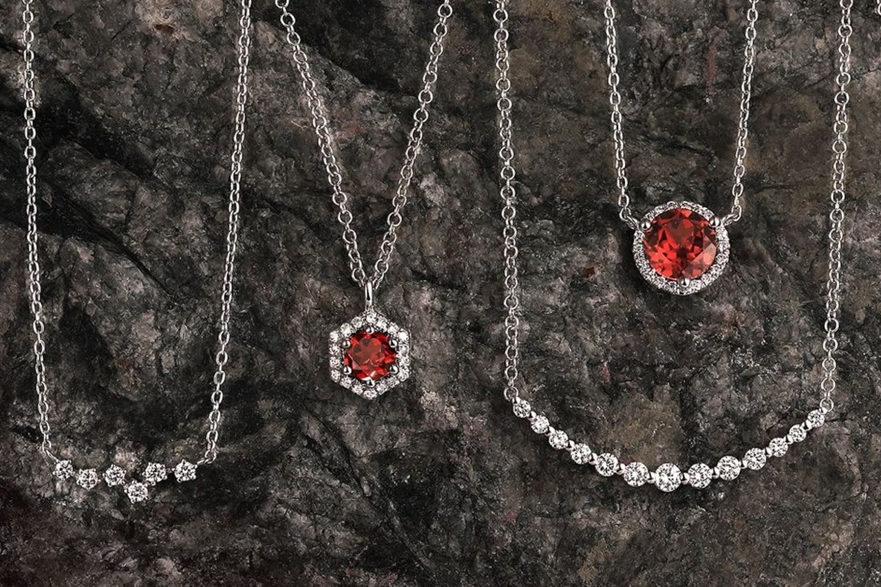 four white gold necklaces featuring diamonds and rubies against a granite background