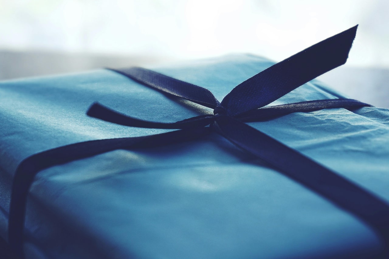 A close-up of a simple yet elegant gift wrapped in blue, adorned with a ribbon.