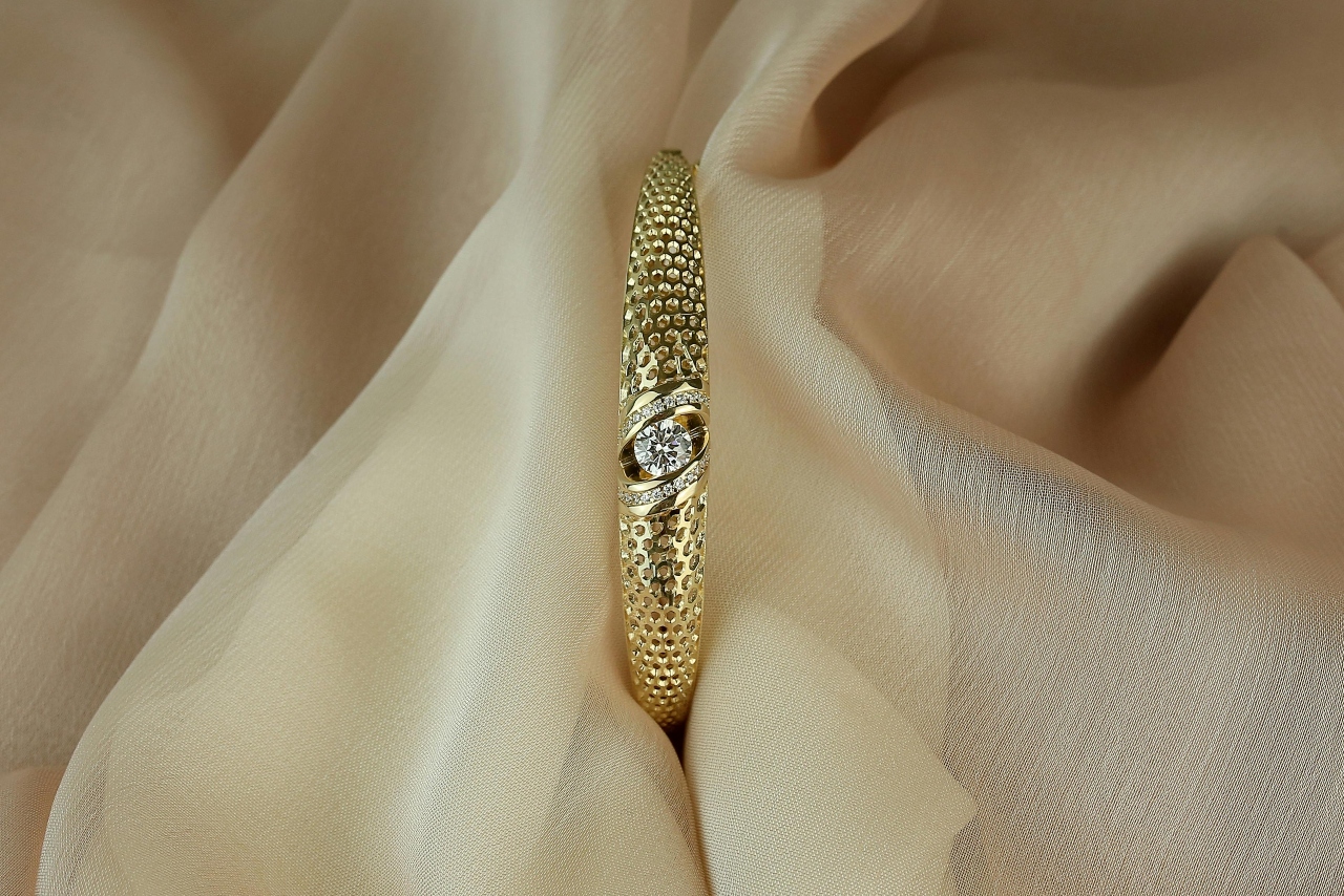 A yellow gold, modern engagement ring with a thick band, sitting on beige fabric.