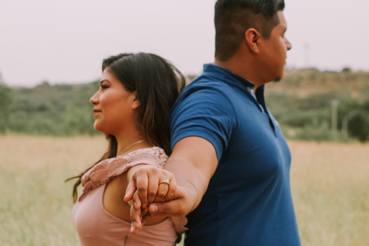 couple holding hands with engagement ring