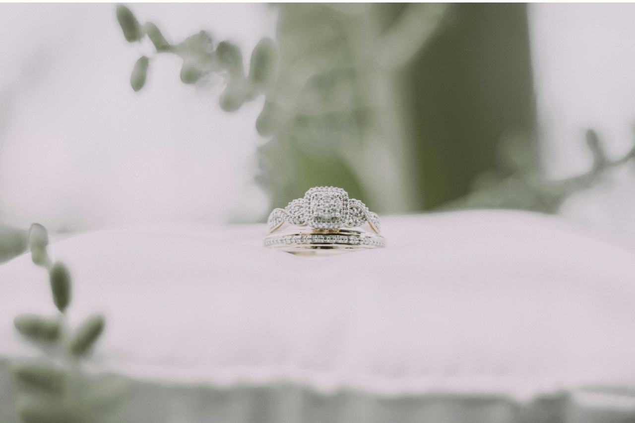 a unique set of engagement rings and wedding bands on a white pillow